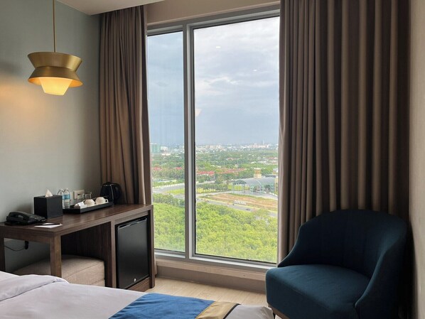 A hotel room with a large window, a desk with a lamp, a chair, and a bed. - Kingsford Hotel Manila Bay (Parañaque)
