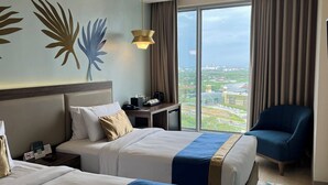 A hotel room with two beds, a desk, a chair, and a large window offering a city view. - Kingsford Hotel Manila Bay (Parañaque)