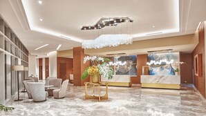 A modern lobby with a marble floor, seating area, reception desk, and decorative elements. - Kingsford Hotel Manila Bay (Parañaque)