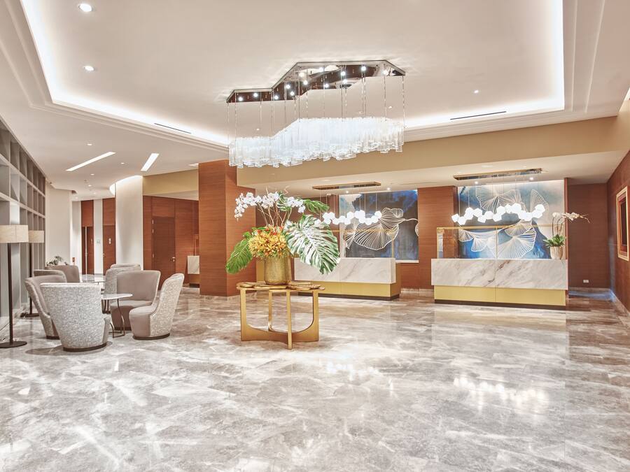 Eine moderne Lobby mit Marmorboden, Sitzgelegenheiten, einer Rezeption und dekorativen Elementen.