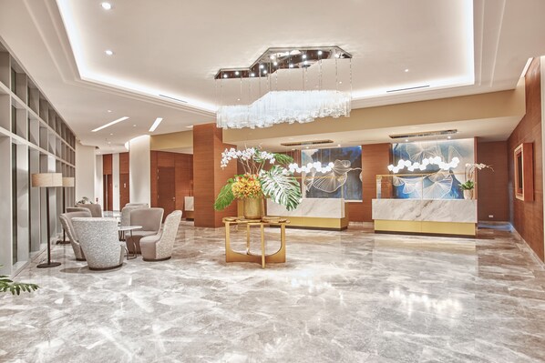A modern lobby with a marble floor, seating area, reception desk, and decorative elements. - Kingsford Hotel Manila Bay (Parañaque)