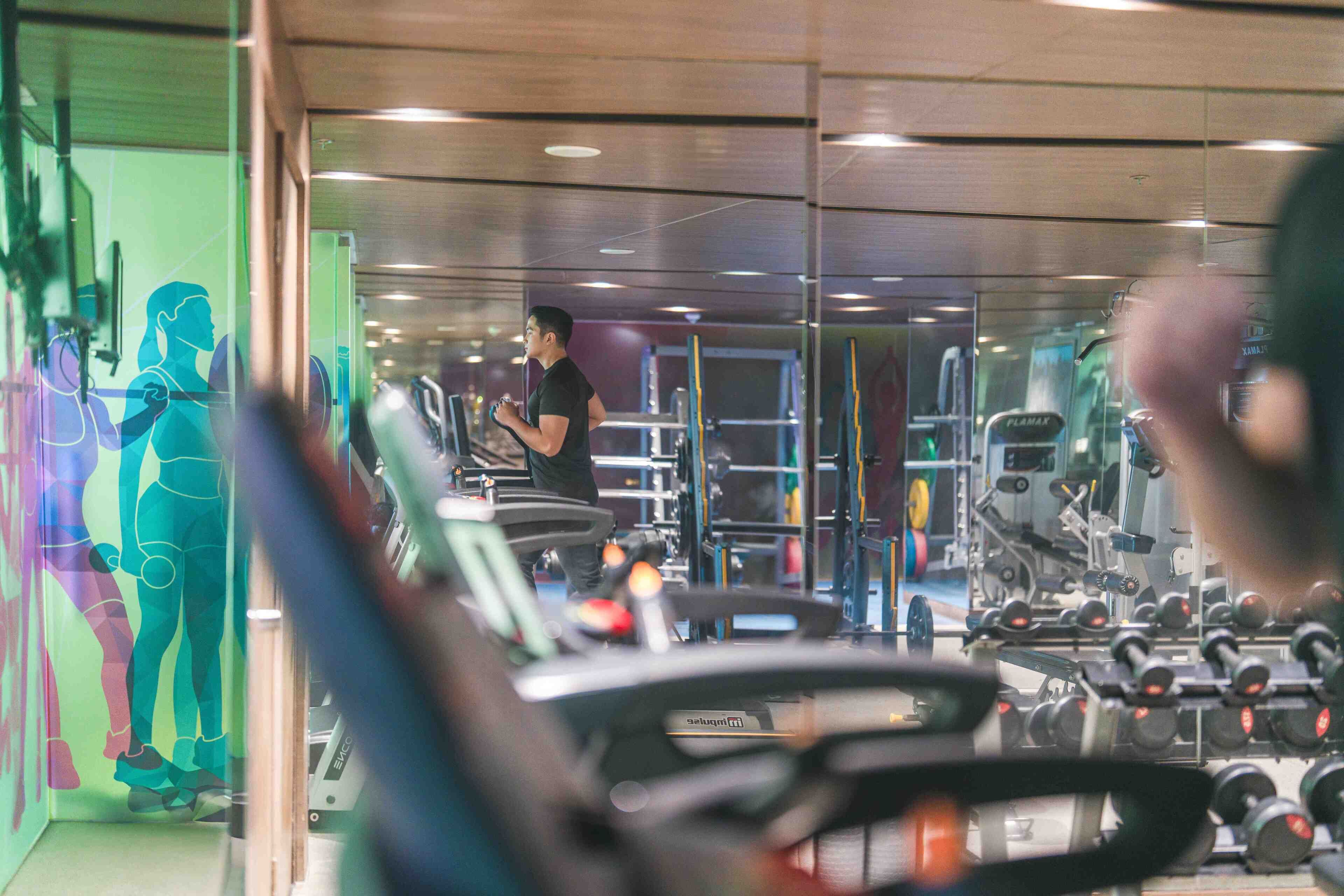 Un gimnasio con equipo de ejercicio y un espejo grande.