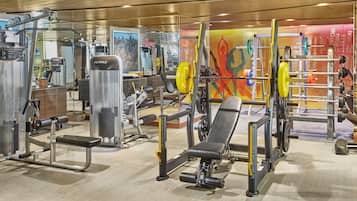 Un gimnasio con diverso equipo de ejercicio, que incluye máquinas de pesas y una prensa de banca.
