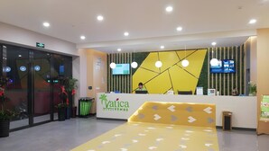 Zona de recepción con un mostrador amarillo, una pantalla digital y un área de asientos con flechas indicativas en el suelo.