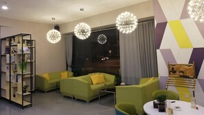Una sala de estar moderna con sofás verdes, una mesa de centro blanca y luces decorativas esféricas.
