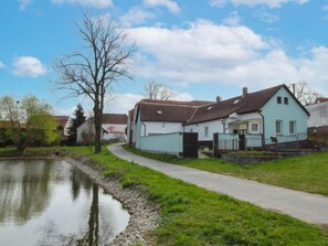 A row of houses by a calm water body, with a paved path leading through the greenery. - Plavsko by Interhome (Plavsko)