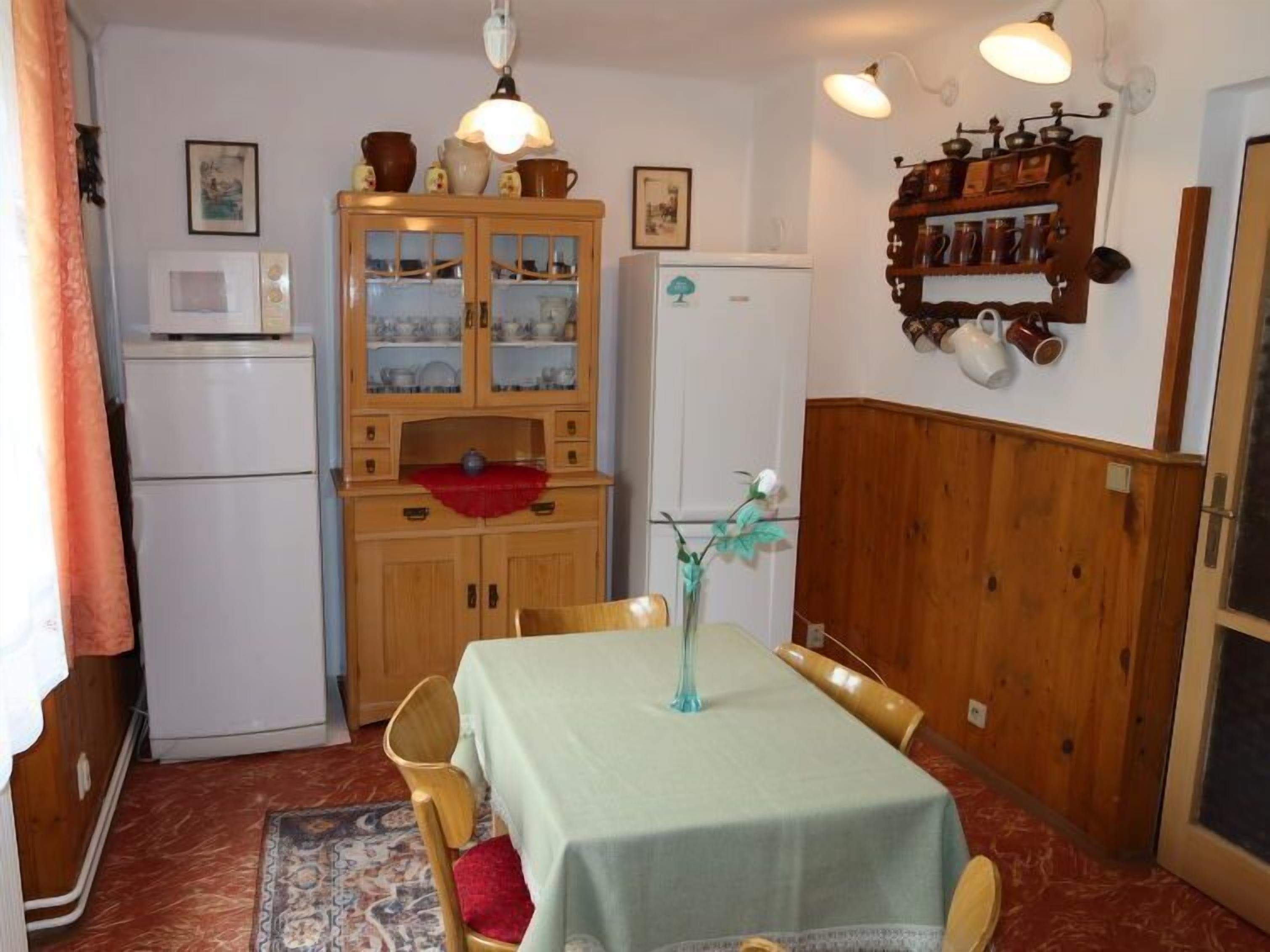 Una cocina compacta con una mesa de comedor, armarios de madera y un refrigerador.