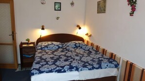 Een slaapkamer met een bed, nachtkastjes, een deur en decoratie aan de muur.
