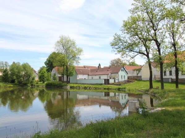 A serene lakeside setting with traditional houses, a calm water body, and lush greenery.