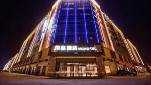 A tall hotel with a prominent entrance and illuminated signage.
