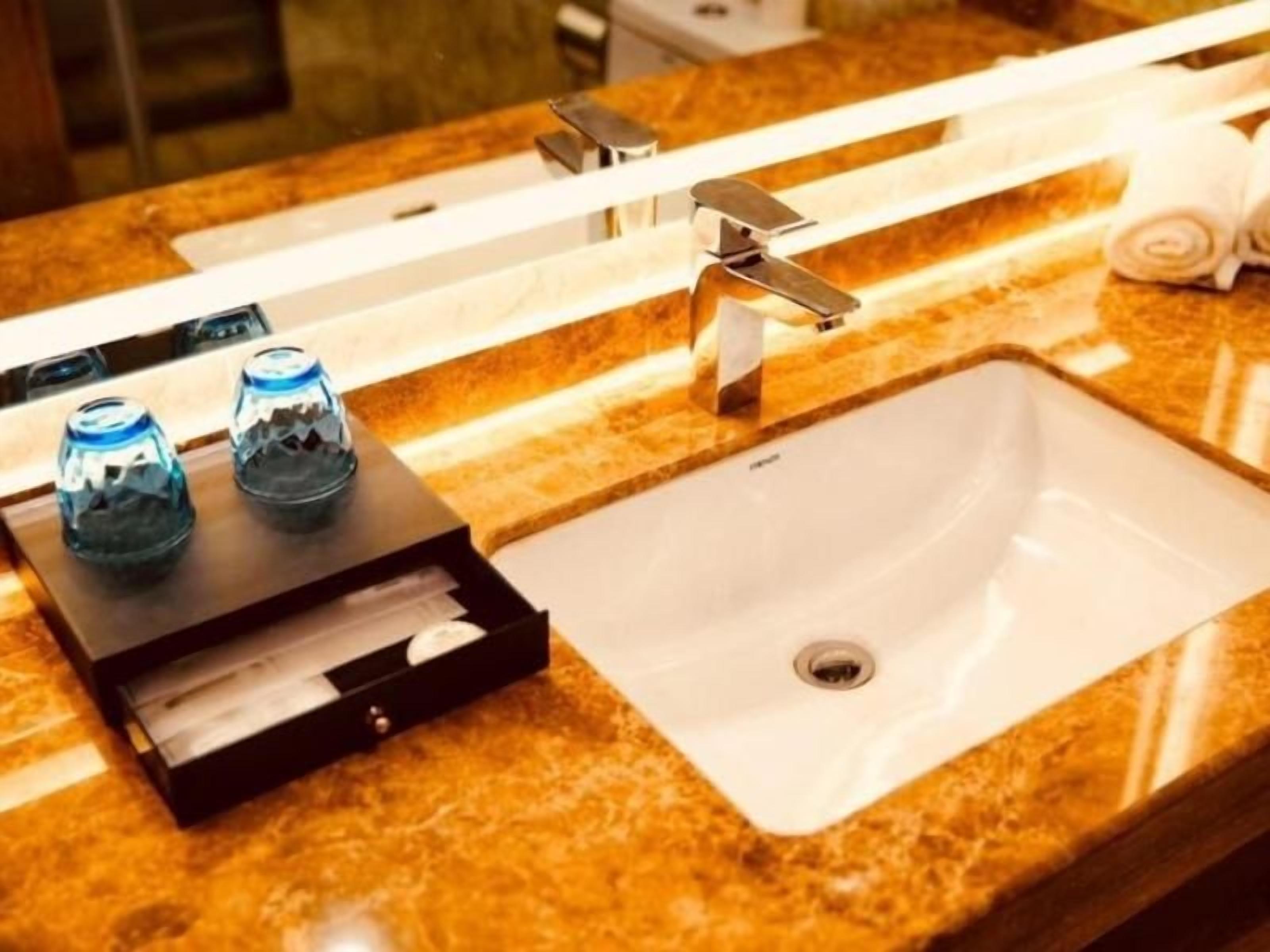 Ein Badezimmer mit Marmorplatte, einem Waschbecken, einem Spiegel und zwei Seifenspendern.