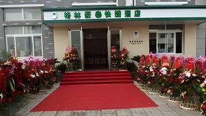 A building entrance with a red carpet leading to the door, surrounded by flower arrangements. - Greentree Inn Shaoxing Xinchang Dafou Express Hotel (Shaoxing)