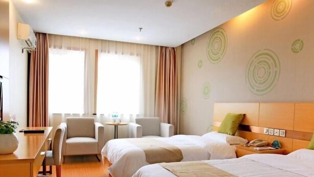 A hotel room with two beds, a desk, a chair, a small table, and a wall with circular patterns.