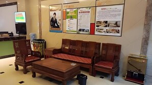 A lobby with traditional wooden furniture, a reception desk, and informational posters on the wall. - Shell Putian Hanjiang District Hanhua West Road Hotel (Putian)