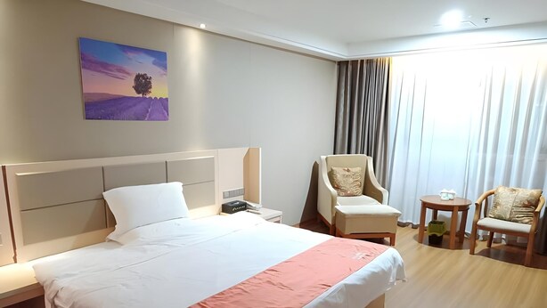 A hotel room with a large bed, a chair, a small table, and a painting on the wall. - Shell Putian Hanjiang District Hanhua West Road Hotel (Putian)