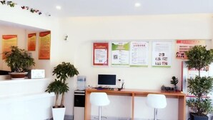 A reception area with a desk, two white chairs, a computer, and several potted plants. - Vatica Hotel Bozhou Qiaocheng District Guogou Guanlantianxia (Bozhou)