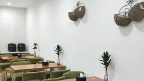 A conference room with green upholstered chairs, wooden tables, and decorative woven baskets on the walls. - Vatica Hotel Bozhou Qiaocheng District Guogou Guanlantianxia (Bozhou)