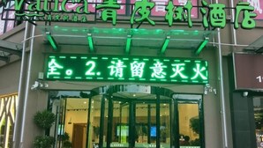 A hotel entrance with a green neon sign indicating room availability and a request for guests to wait. - Vatica Hotel Bozhou Qiaocheng District Guogou Guanlantianxia (Bozhou)