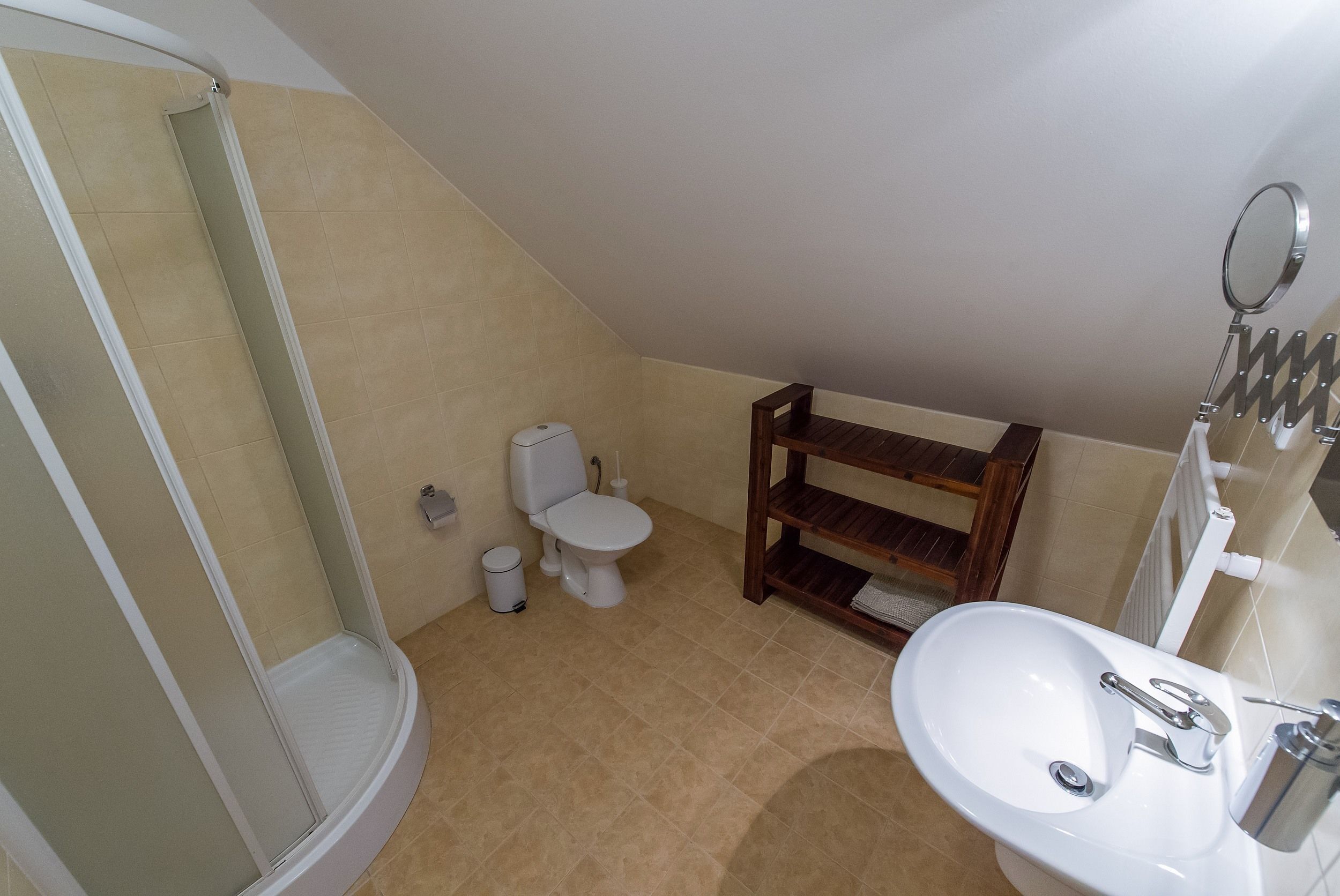 A bathroom with a shower, toilet, sink, and a shelf.