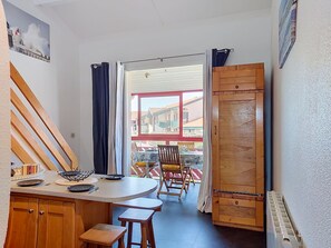 Une cuisine avec des meubles de rangement en bois, une table à manger avec des chaises et une vue sur l’extérieur.