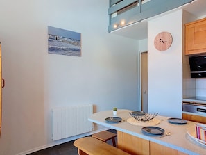 Een moderne keuken met een wit aanrecht, een klok, een kleine plant en uitzicht op zee door een raam.
