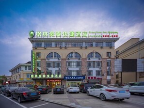 A hotel with multiple floors, large windows, and a parking lot with several cars. - Greentree Inn Wuxi Yixing Xushe Town Government Ex (Wuxi)
