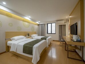 A hotel room with two beds, a desk, a TV, and a window with curtains.