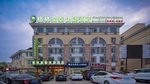A hotel with multiple floors, large windows, and a parking lot with several cars. - Greentree Inn Wuxi Yixing Xushe Town Government Ex (Wuxi)