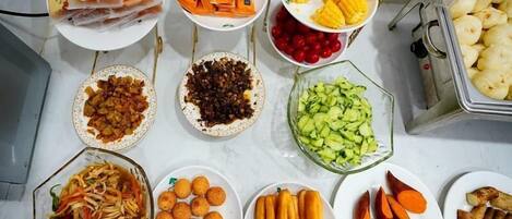 A variety of food items including corn, sweet potatoes, and various fruits and vegetables arranged on a table.