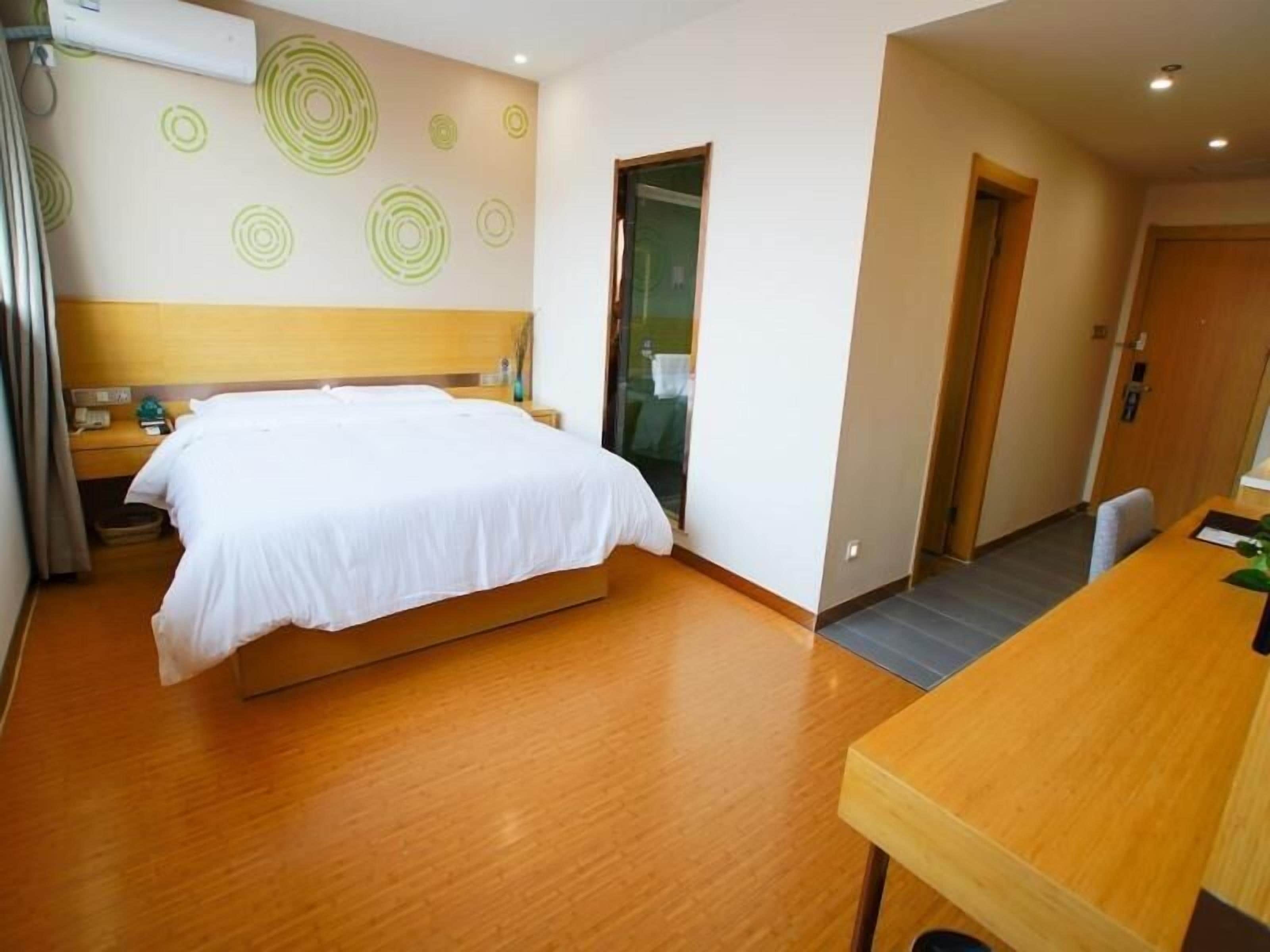 Une chambre d’hôtel avec un lit, une table de chevet et un bureau en bois.