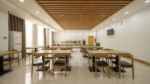 A modern conference room with wooden tables and chairs, a flat-screen TV on the wall, and a kitchen area in the background. - Greentree Inn Wuxi Yixing Xushe Town Government Ex (Wuxi)