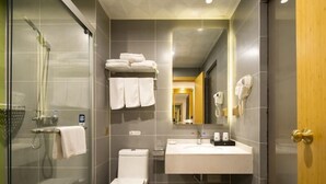A modern bathroom with a glass shower enclosure, a toilet, a sink with a mirror, and a towel rack with folded towels. - Greentree Inn Wuxi Yixing Xushe Town Government Ex (Wuxi)