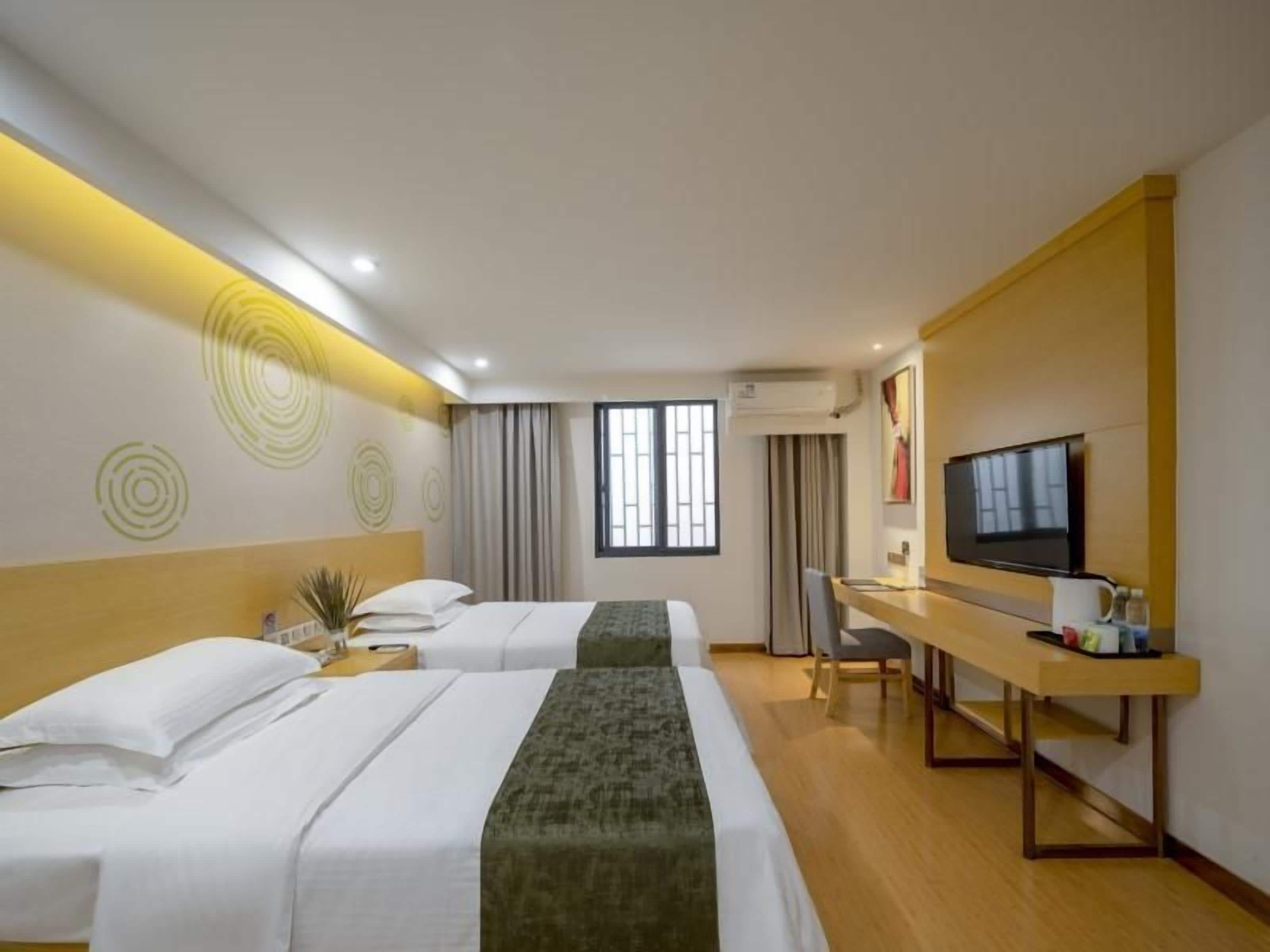 Une chambre d’hôtel avec deux lits, un bureau, une télévision et une fenêtre.