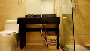 A bathroom with a toilet, a sink with a mirror, a shower area, and a basket. - Shell Xizhou Xifu District West Heping Street Hotel (Xinzhou)