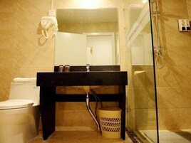 Un baño con inodoro, lavabo con espejo, zona de ducha y una cesta.