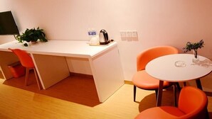A compact kitchen with a white countertop, two orange chairs, a small table, and a potted plant. - Shell Xizhou Xifu District West Heping Street Hotel (Xinzhou)