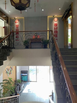 A hotel lobby with a staircase, a reception desk, and a view of the outside. - Shell Shanghai Chedun Yingshi City Yingshi Road Hotel (Shanghai)