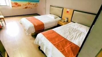 A hotel room with two beds, a mural of a beach scene, and a wooden floor.