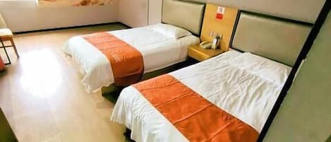 Une chambre d’hôtel avec deux lits, une fresque représentant une scène de plage et un plancher en bois.