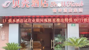 The exterior of a hotel with a glass entrance, potted plants in front, and a sign indicating it is part of the '格林酒店集团'. - Shell Shanghai Chedun Yingshi City Yingshi Road Hotel (Shanghai)