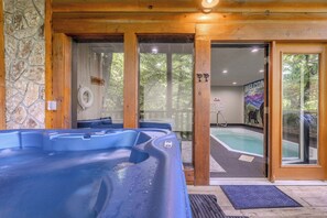 A hot tub area with a stone wall, wooden beams, and a pool with a 'Welcome' sign.