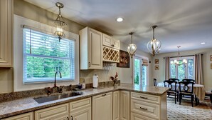 Cocina con armarios blancos, encimeras de granito e iluminación colgante.
