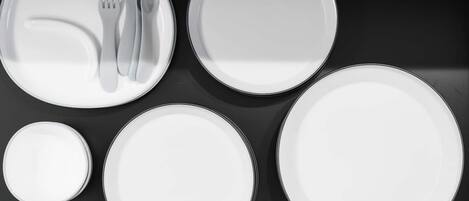 A set of white plates and cutlery arranged on a black surface.