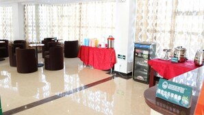 Vestíbulo de hotel con una mesa roja, zona de estar y estación de bebidas.