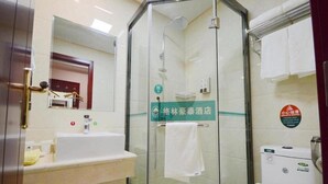 Un baño moderno con ducha de vidrio, un lavabo con espejo y un inodoro.