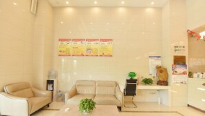 Un vestíbulo de hotel con una recepción, dos sofás, una máquina de café y un dispensador de agua.