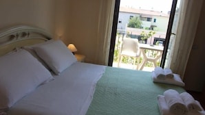 Una habitación de hotel con una cama, un edredón verde y dos toallas enrolladas en el suelo.