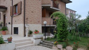 A multi-story brick building with balconies, a small garden area with steps leading to the entrance, and potted plants. - B&B La Tartaruga (Civitanova Marche)
