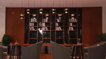 A lobby with a central seating area, a bookshelf, and pendant lighting.
