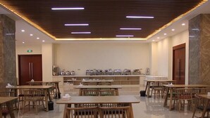 A spacious dining area with wooden tables and chairs, a marble floor, and a modern ceiling with linear lighting. - Greentree Eastern Liaocheng Linqing City Yandian Hotel (Liaocheng)